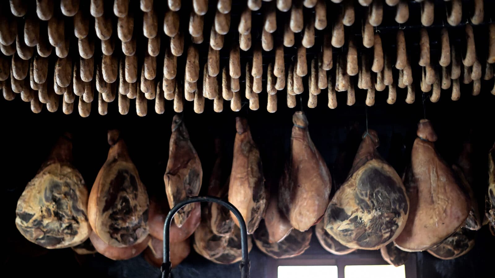 Presuntos pendurados e fileiras de alheiras a curar num fumeiro tradicional do Barroso