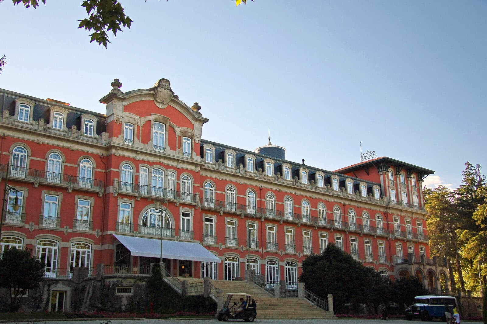 Fachada rosa e cinzenta do Vidago Palace, com a escadaria de entrada, visto do parque de Vidago