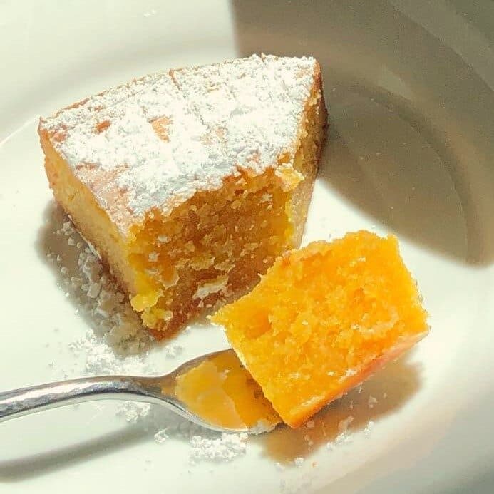 Fatia de toucinho-do-céu polvilhada com açúcar em pó, num prato, com um pedaço espetado num garfo