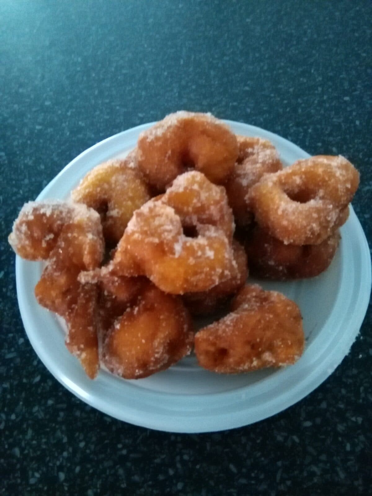 Fritos de abóbora polvilhados com açúcar, num prato branco