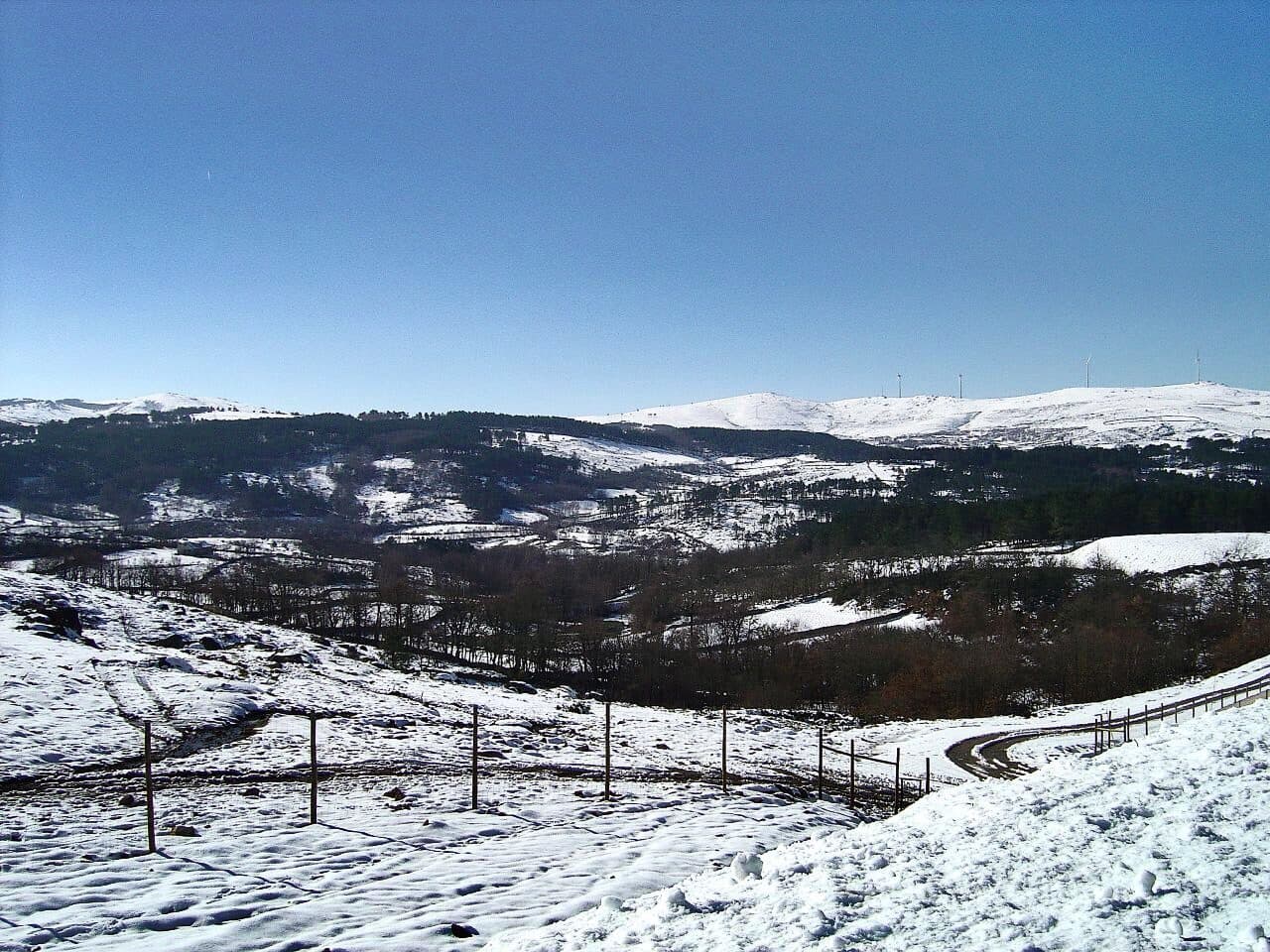 Planalto da serra do Alvão coberto de neve, com serras brancas ao fundo e céu azul