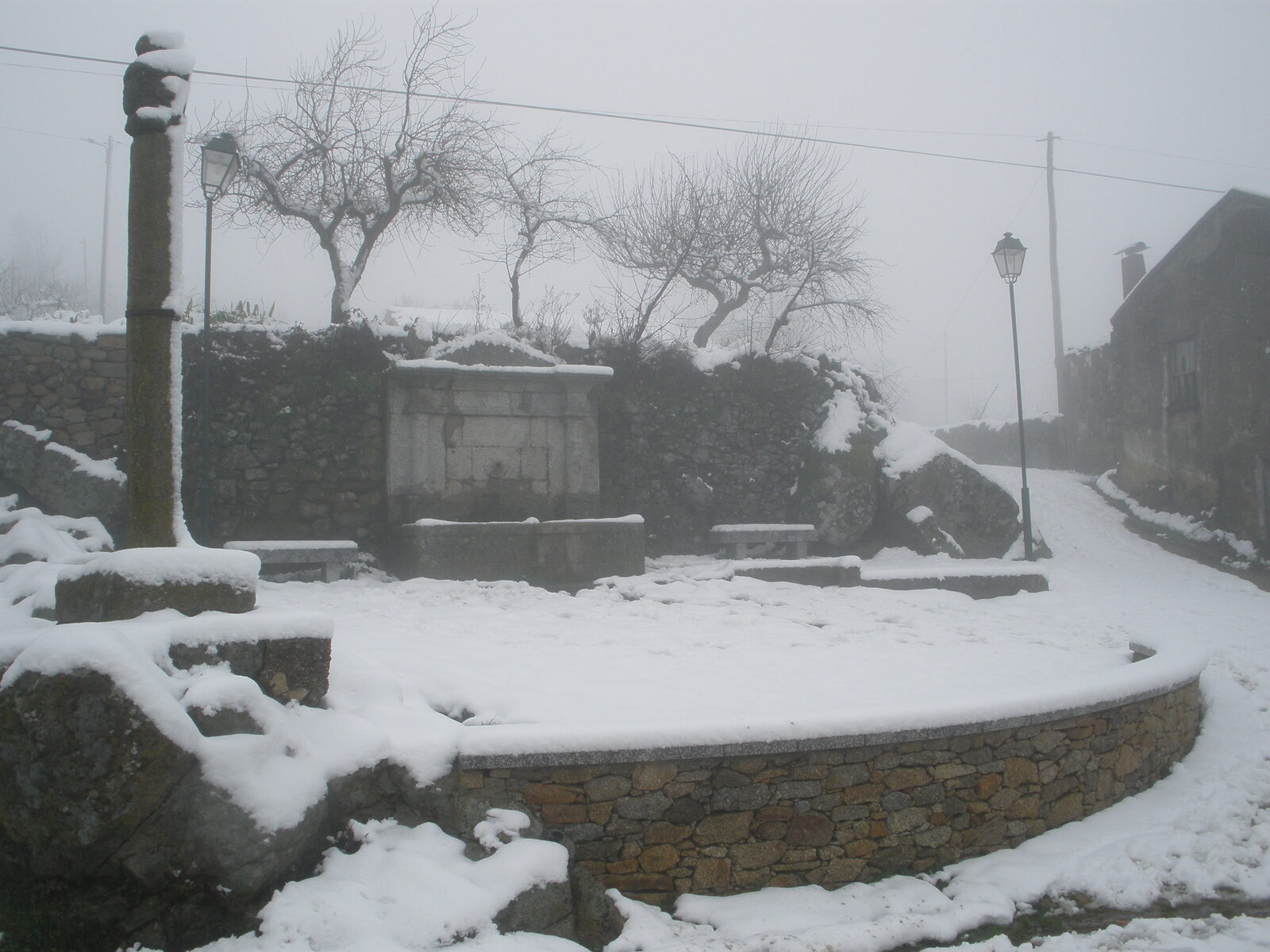 Pelourinho de Rebordainhos e o largo da aldeia cobertos de neve, num dia de nevoeiro