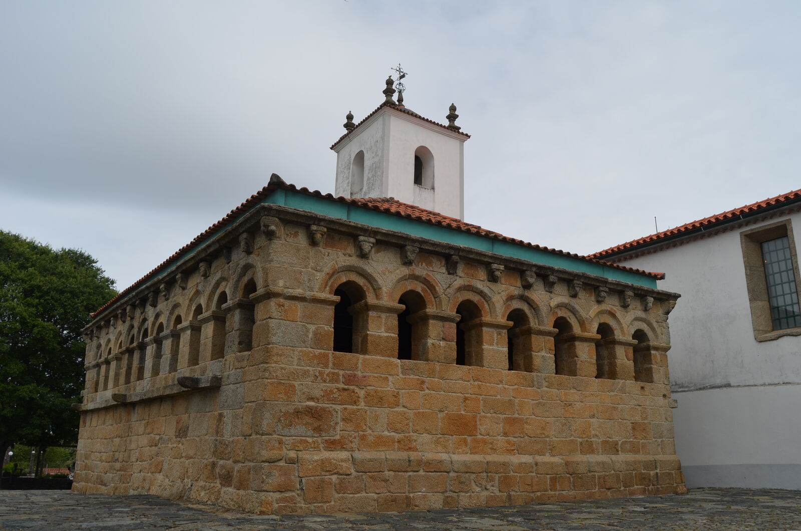 A Domus Municipalis de Bragança, edifício românico de granito com uma fiada de arcos, e a torre sineira da Igreja de Santa Maria