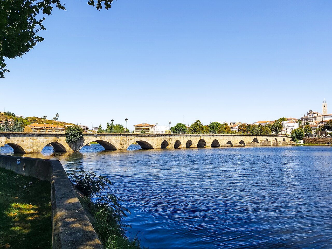 A ponte velha de Mirandela, em granito, com os arcos sobre o rio Tua e a cidade ao fundo