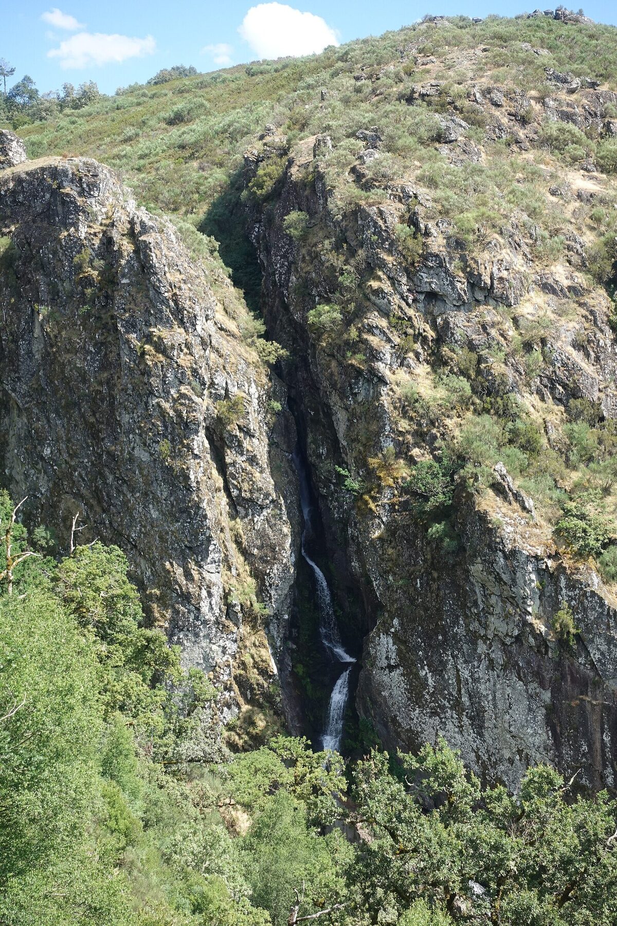 Cascata de Pitões das Júnias a cair numa garganta de granito, rodeada de mato e árvores