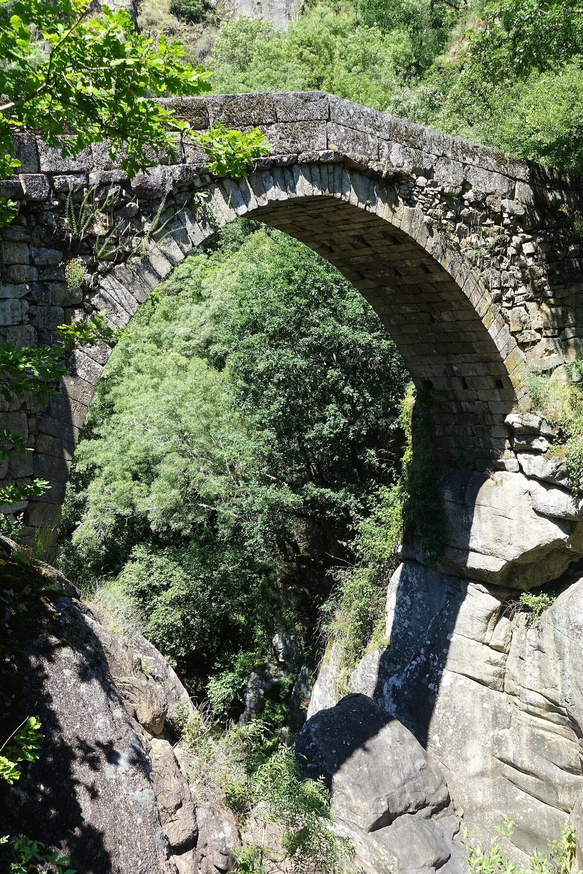 Ponte da Misarela, de um só arco em pedra, sobre um desfiladeiro de granito coberto de vegetação