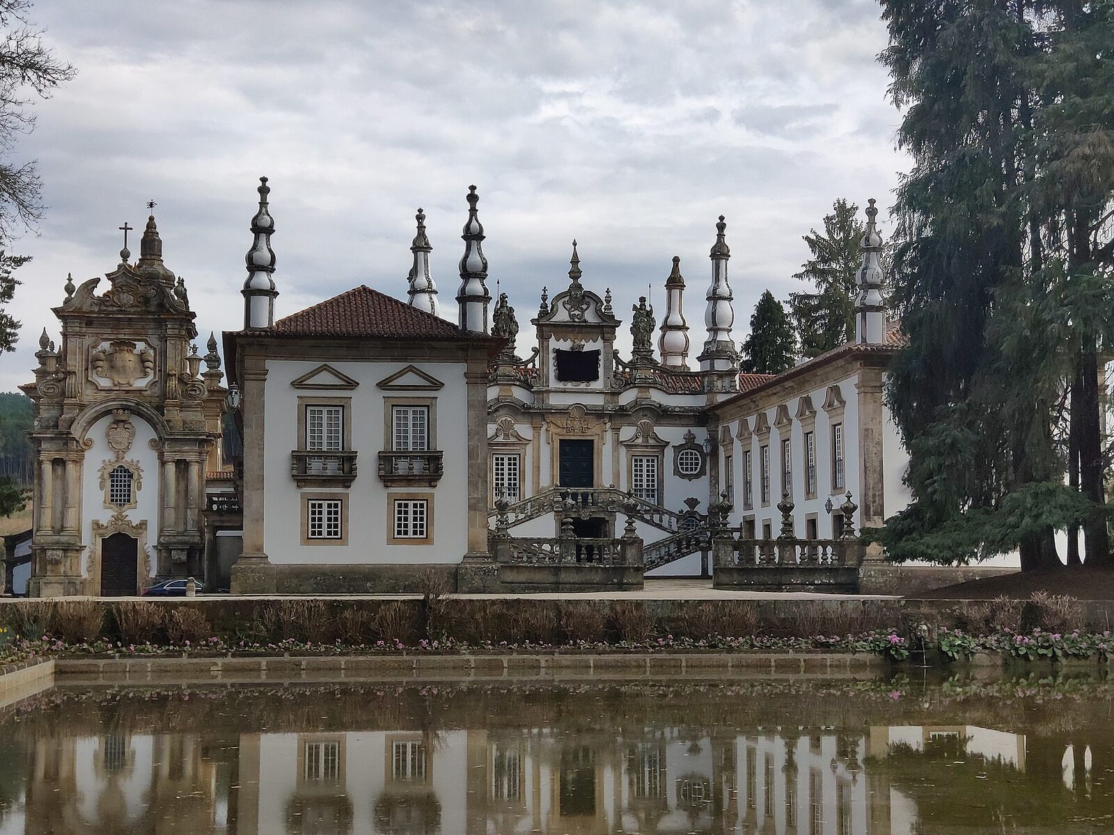 Fachada barroca da Casa de Mateus, com pináculos e escadaria, reflectida no lago do jardim