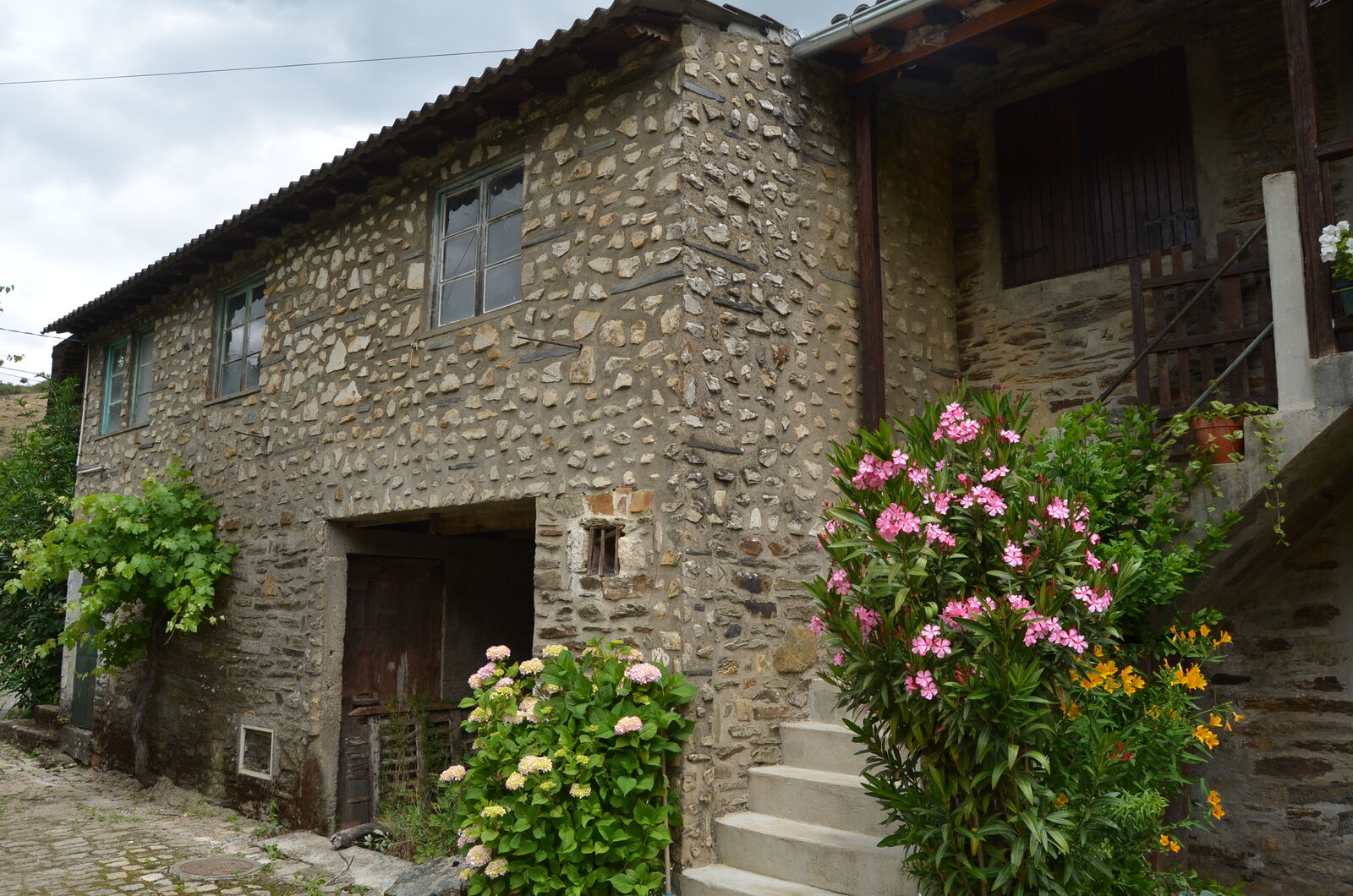 Casa tradicional de xisto com varanda de madeira e flores à porta