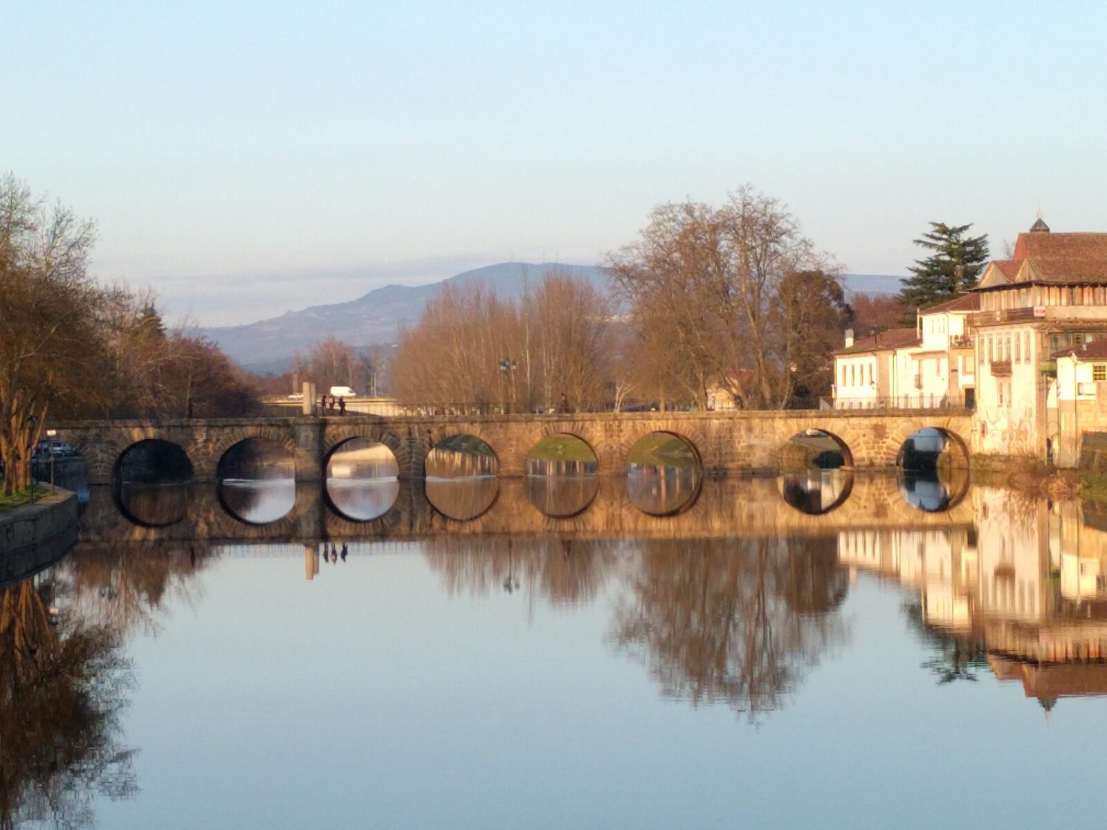 Ponte romana de Trajano, com os arcos reflectidos no rio Tâmega e casario à direita